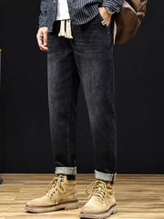 Men's relaxed fit black cotton jeans with drawstring detail and cuffed hems.