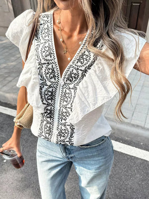 White embroidered ruffled V-neck shirt with short sleeves and a zip front.