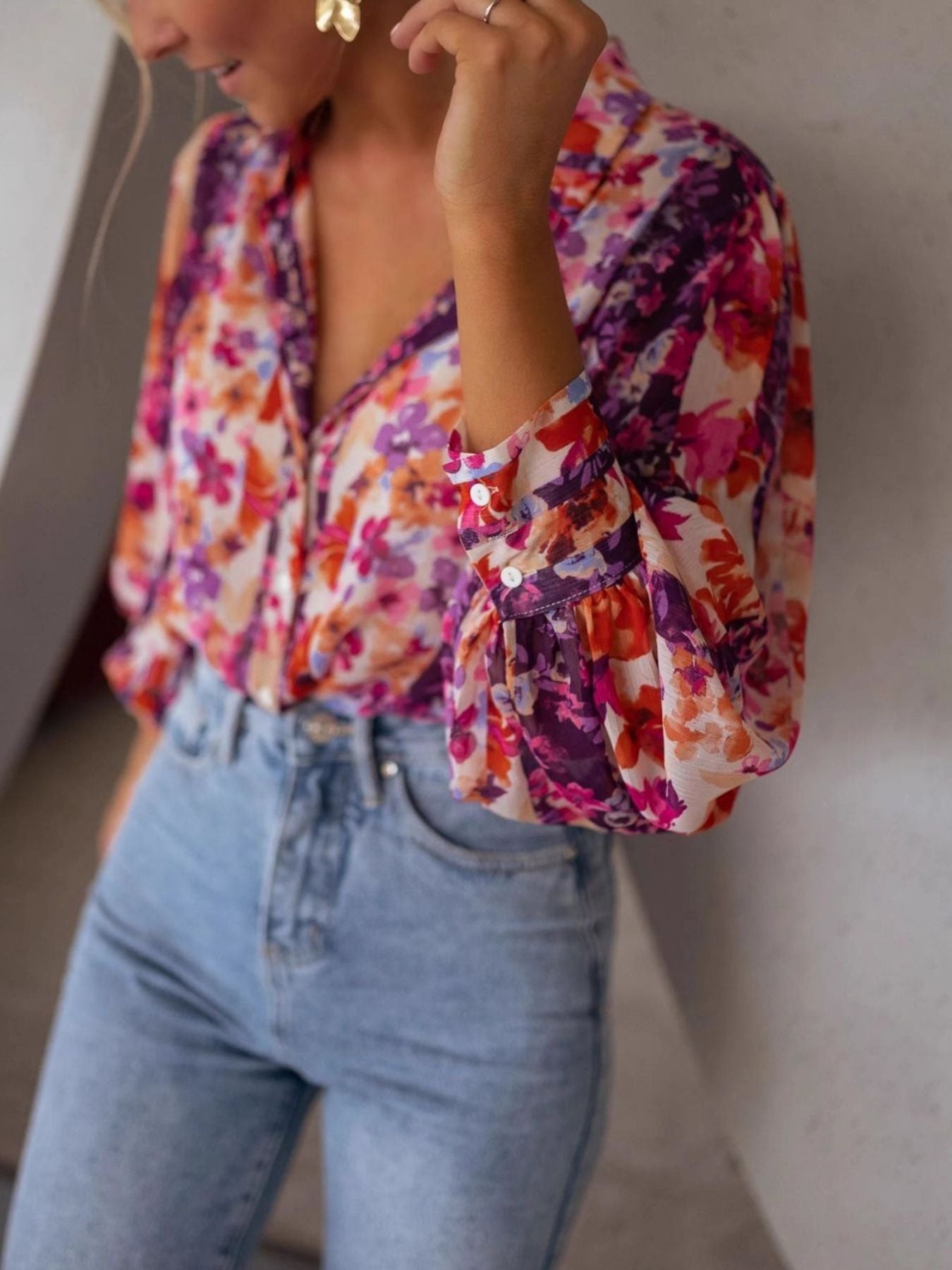 Vibrant floral print button-up shirt with bishop sleeves and button cuffs, styled with denim.