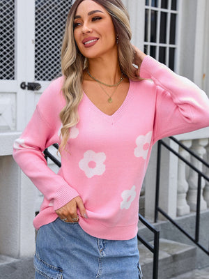 Pink v-neck knit sweater with white daisy print, long sleeves, and ribbed cuffs.