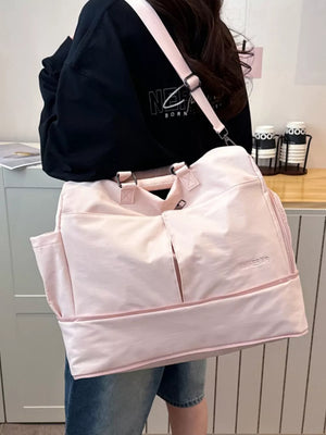 Pink multi-pocket travel bag with adjustable strap and exterior pockets.