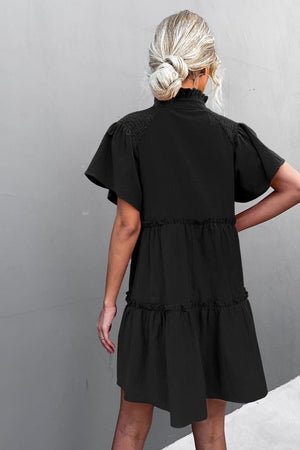 Black tiered ruffle sleeve trapeze dress with smocked yoke and mock neck.