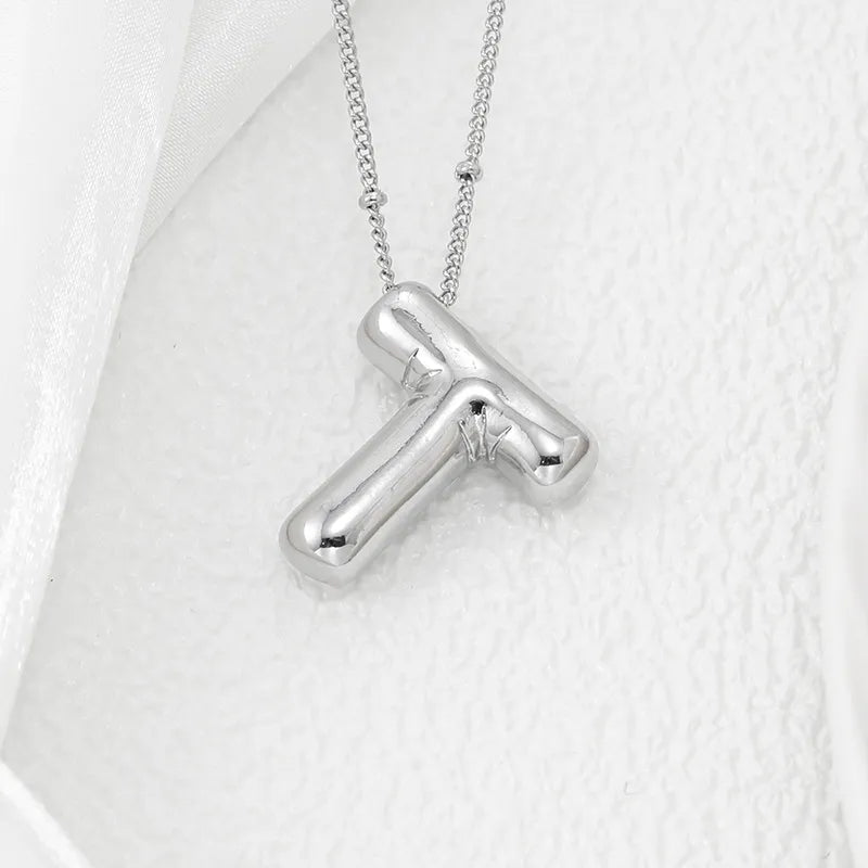 Silver letter T pendant necklace with a chunky, rounded design on a delicate chain.