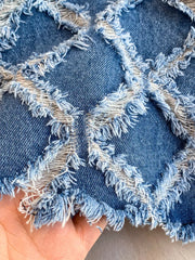 Distressed denim shorts with frayed diamond cutouts and raw hem detail.