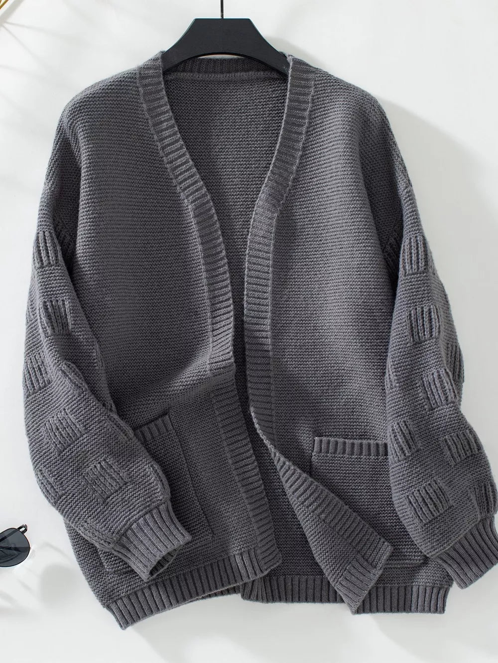 Dark gray chunky knit open-front cardigan with pockets and textured sleeves.