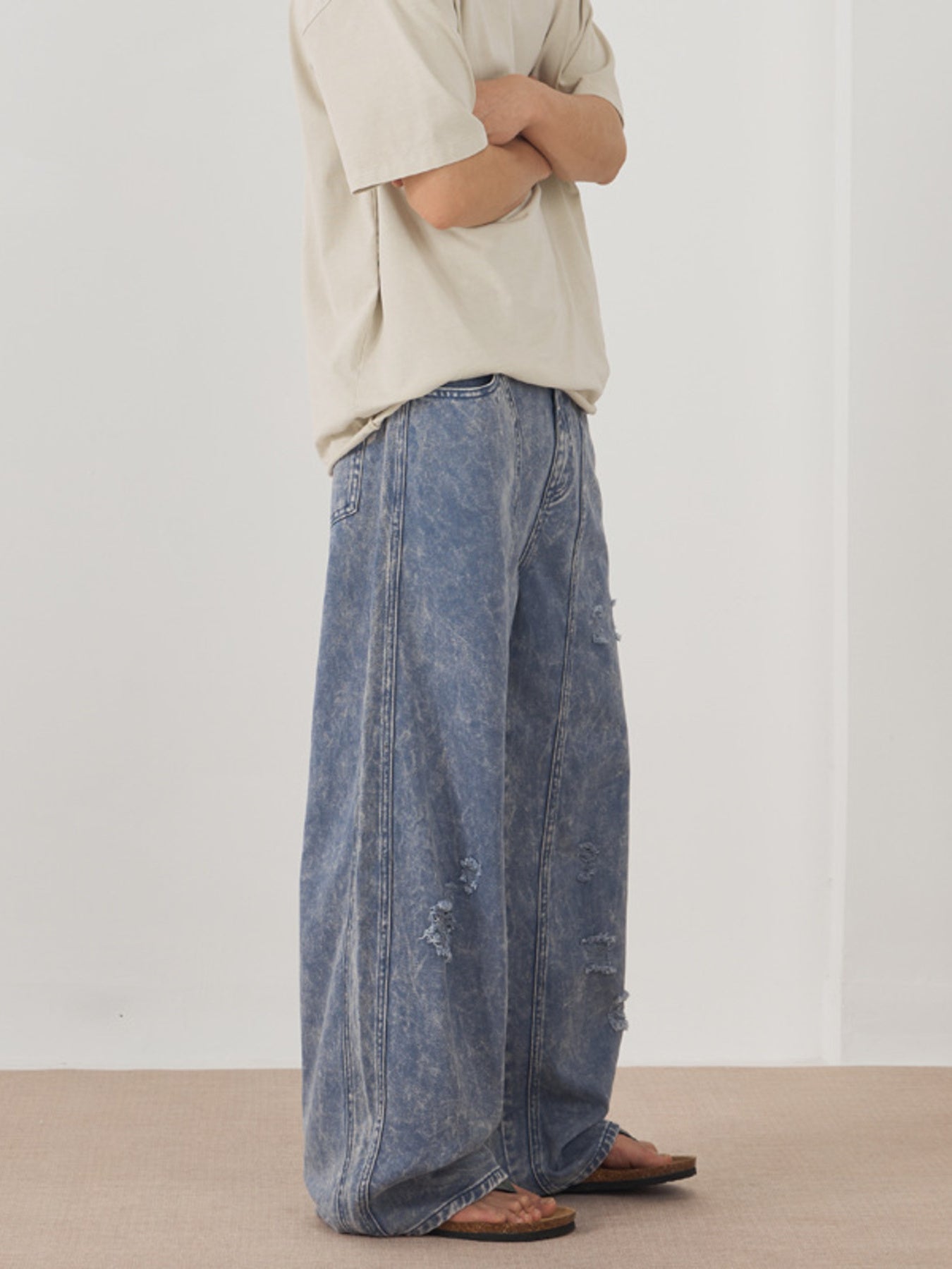 Men's blue acid wash distressed wide-leg denim jeans with a casual fit.