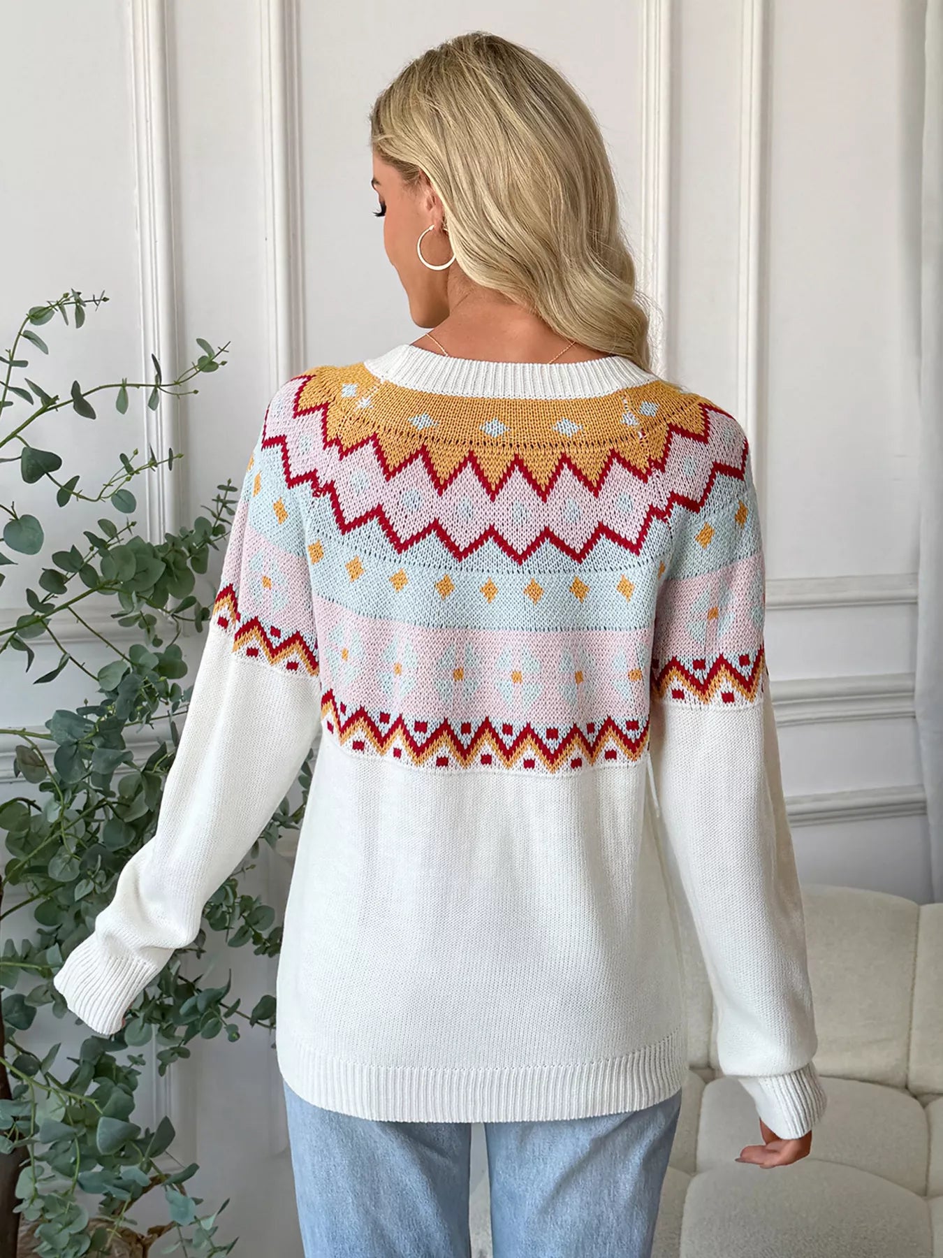 White geometric knit long-sleeve sweater with colorful fair isle pattern detail.