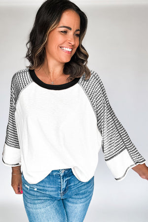 Textured raglan sleeve tee in white with black houndstooth sleeves and black neckline.