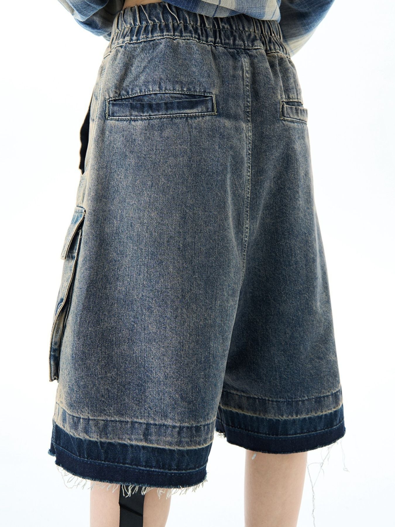 Blue denim cargo shorts with elastic waist and distressed hem detail.