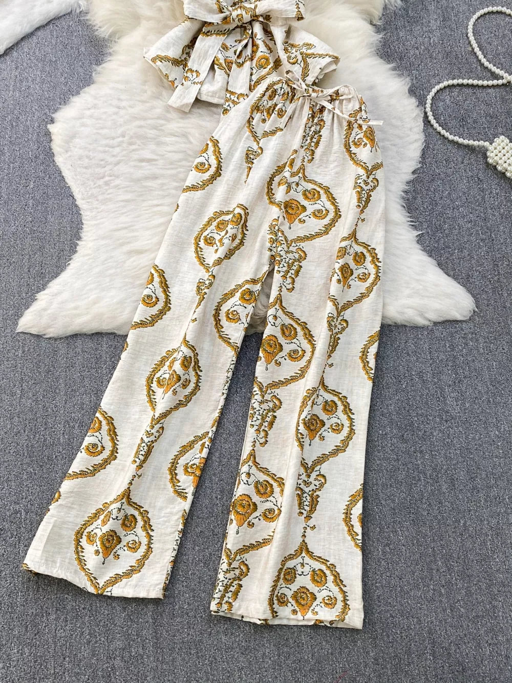 Tropical print two-piece set with wide-leg pants and belted detail in cream with yellow pattern.