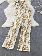 Tropical print two-piece set with wide-leg pants and belted detail in cream with yellow pattern.