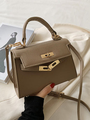 Khaki mini crossbody bag in textured faux leather with gold hardware and top handle.