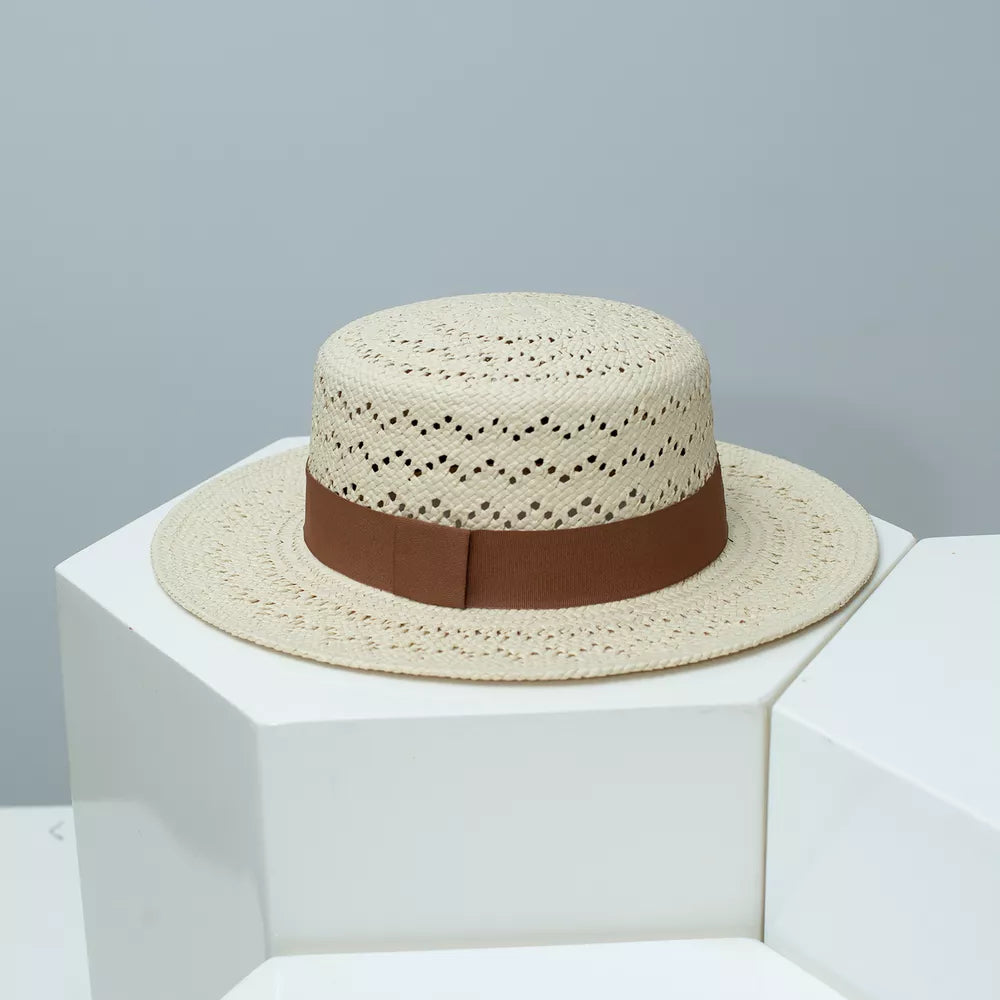 Classic woven straw boater hat in off-white with brown ribbon band and breathable eyelet pattern.