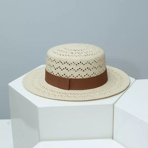 Classic woven straw boater hat in off-white with brown ribbon band and breathable eyelet pattern.