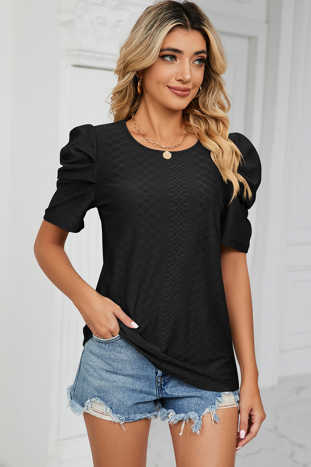 Black perforated puff sleeve top with textured fabric and round neckline.