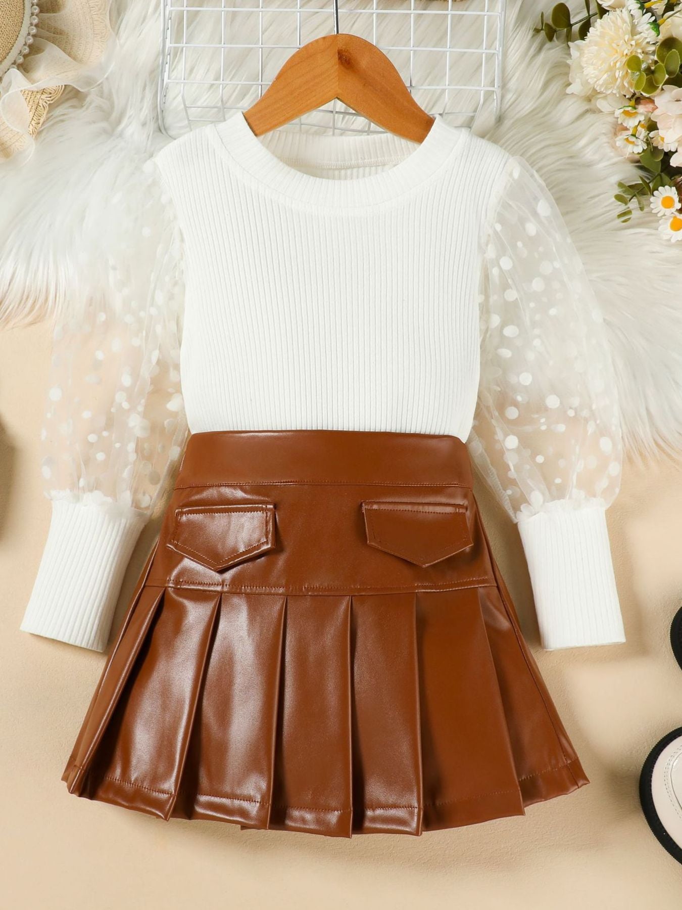 White ribbed top with polka dot sheer sleeves and brown faux leather pleated skirt.