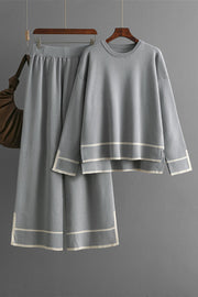 Gray acrylic loungewear set with round neck top and sweater pants, featuring cream trim detail.
