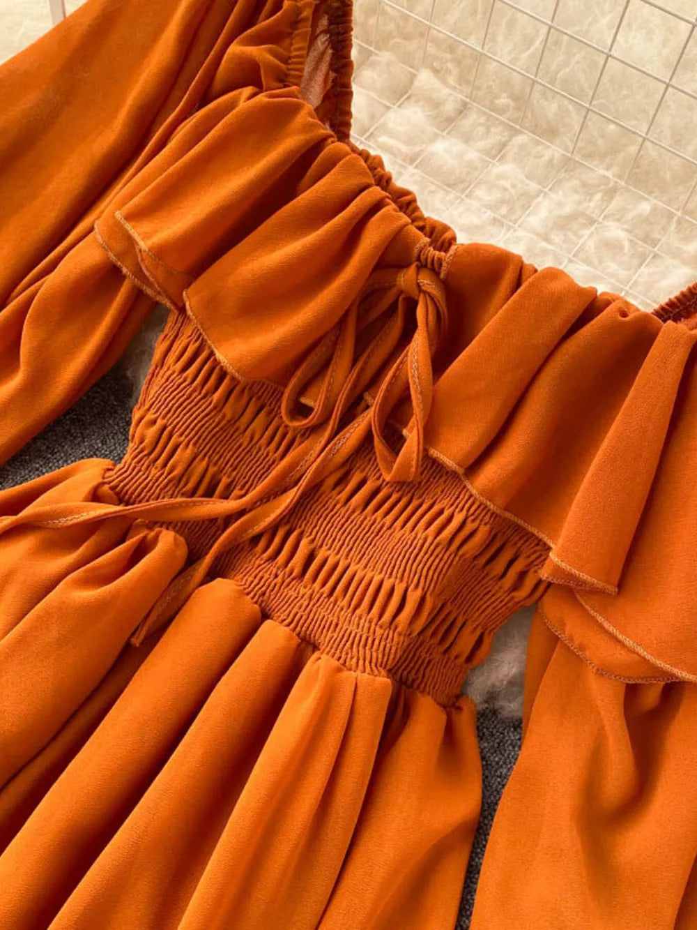 Orange maternity dress with square neck, ruffled detail, smocked bodice, and balloon sleeves.
