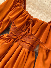 Orange maternity dress with square neck, ruffled detail, smocked bodice, and balloon sleeves.