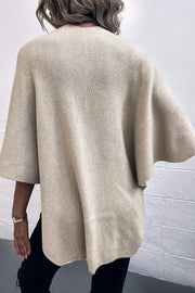Taupe knit cape with wide sleeves and ribbed texture.
