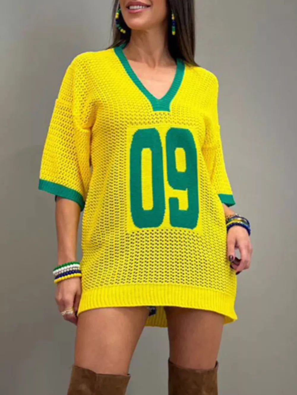 Yellow openwork knit tunic sweater with green trim and large '09' graphic.