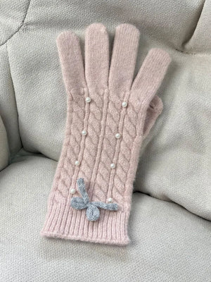 Blush pink cable knit gloves with pearl embellishments and a grey bow detail.