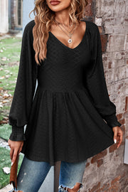 Black textured blouse with V-neck, empire waist, and shirred long sleeves.