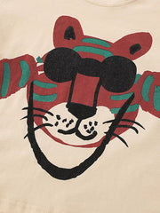 Cream cotton baby tee with a whimsical red tiger graphic and black sunglasses.