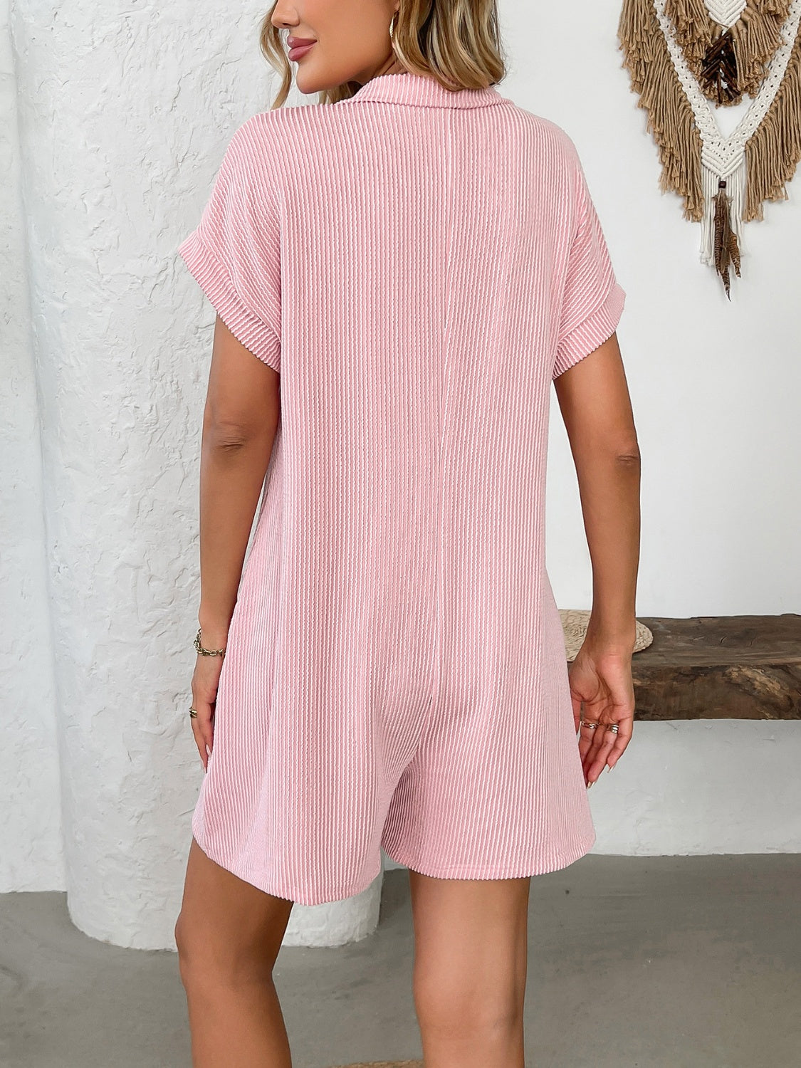 Ribbed knit romper in blush pink with short sleeves and collar.