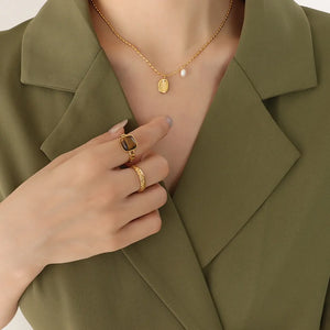 Gold oval medallion and pearl accent necklace with matching rings.