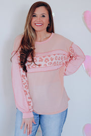 Blush pink waffle knit top with leopard print panels and long sleeves.