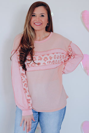 Blush pink waffle knit top with leopard print panels and long sleeves.