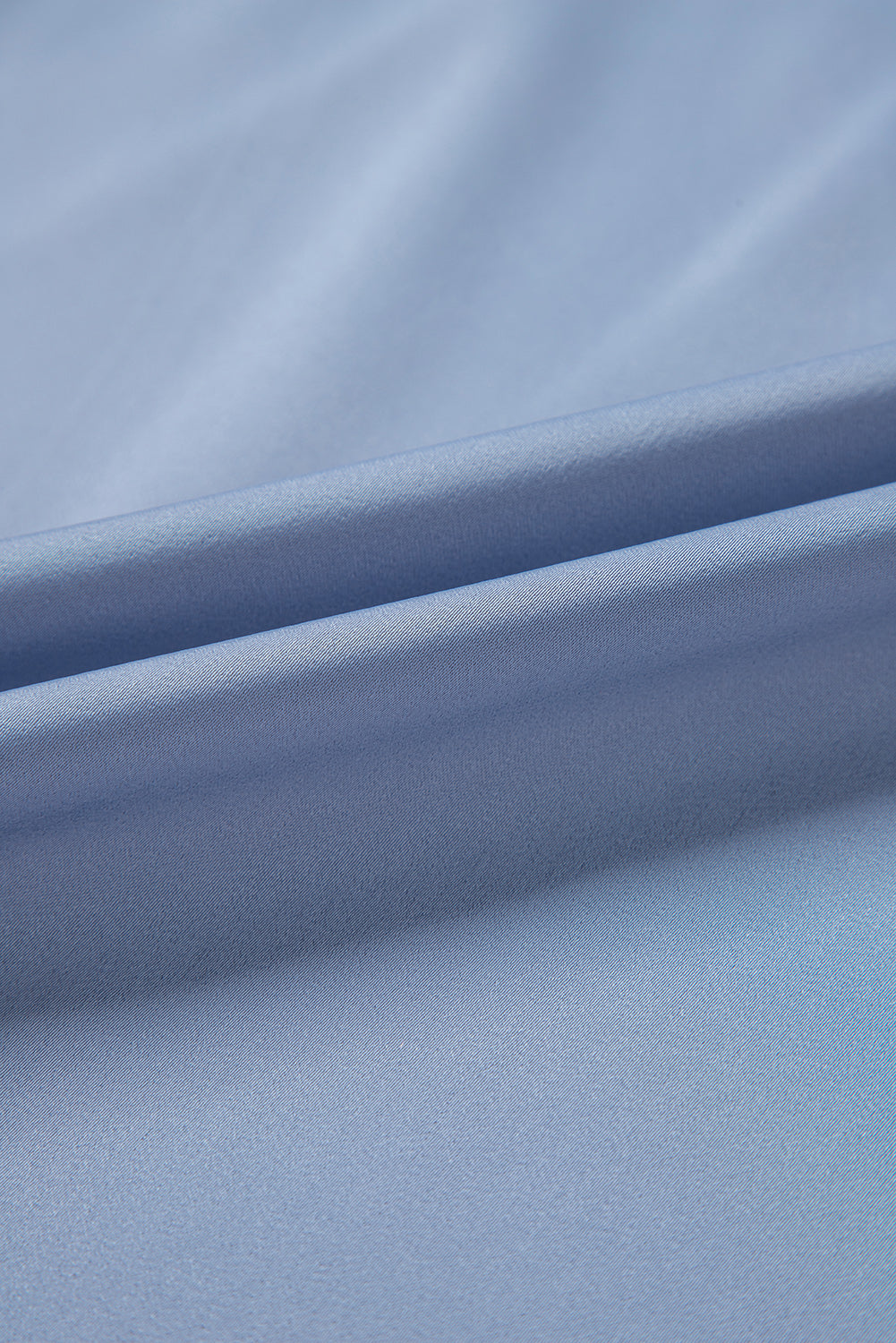 Dusty blue blouse with draped neckline and bell sleeves, showing fabric texture.