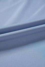 Dusty blue blouse with draped neckline and bell sleeves, showing fabric texture.