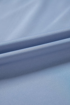 Dusty blue blouse with draped neckline and bell sleeves, showing fabric texture.