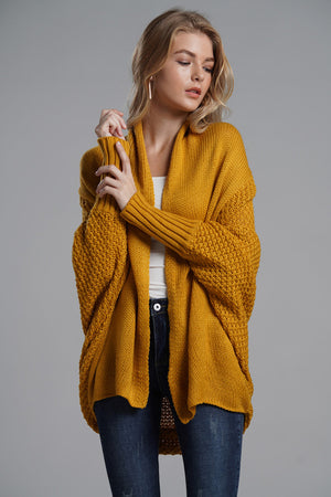 Mustard acrylic cocoon knit sleeve cardigan with textured sleeves and ribbed cuffs.