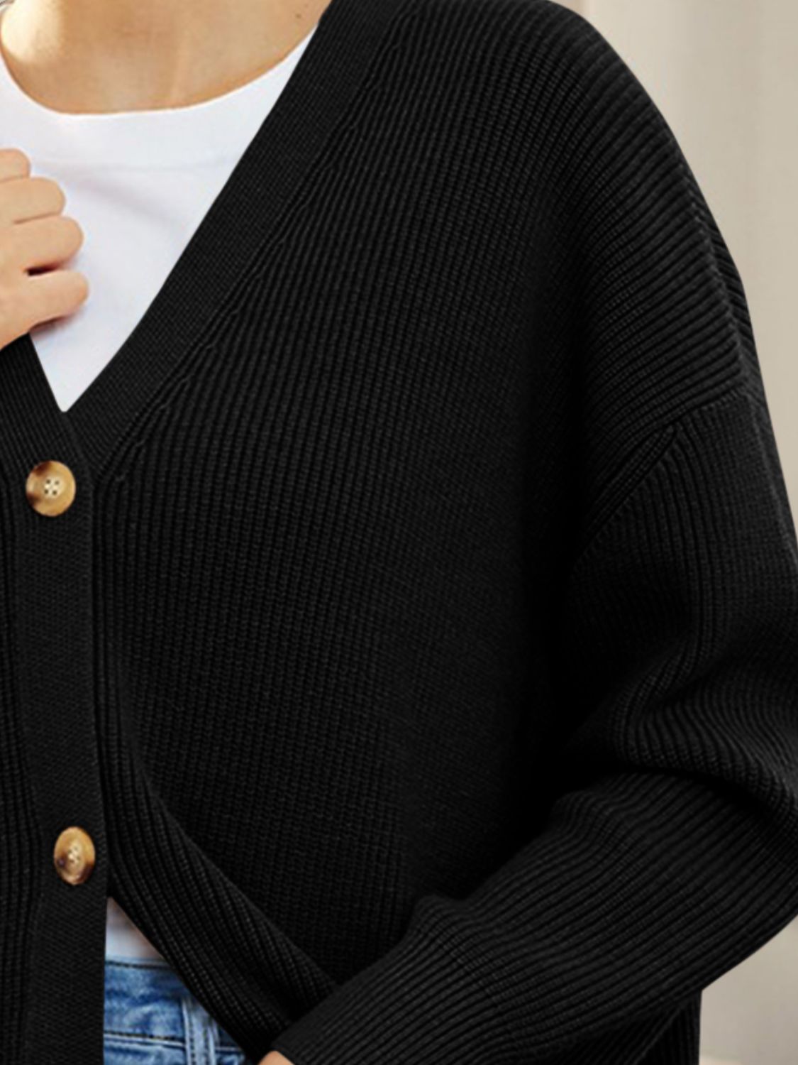 Black ribbed knit cardigan with balloon sleeves and button front, styled over a white tee.