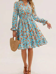 Pastel blue floral dress with smocked waist, ruffled cuffs, and hem.
