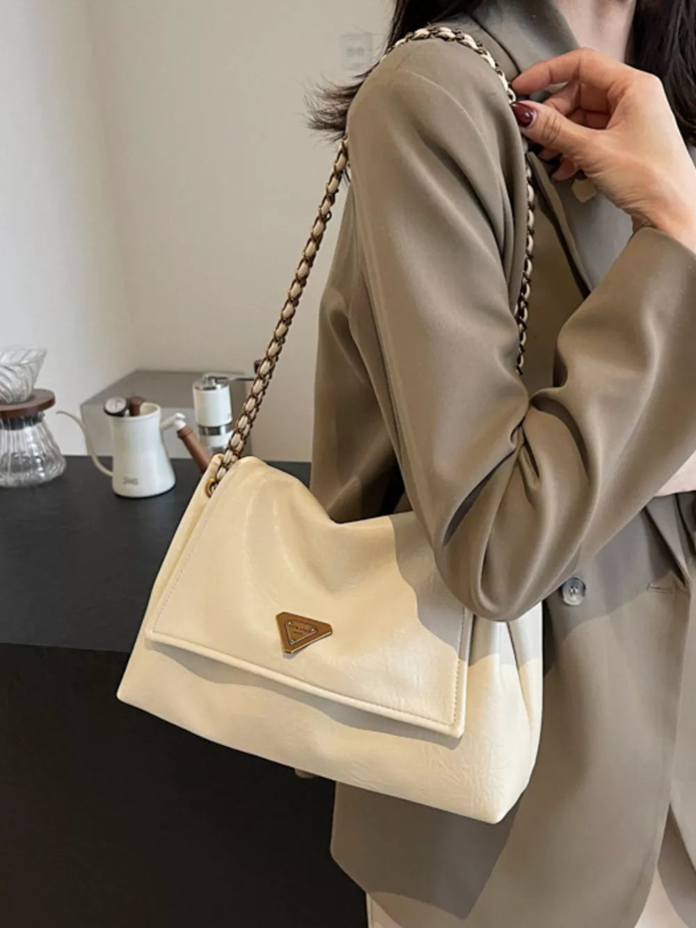 Off-white shoulder bag with flap, chain detail, and triangle logo.