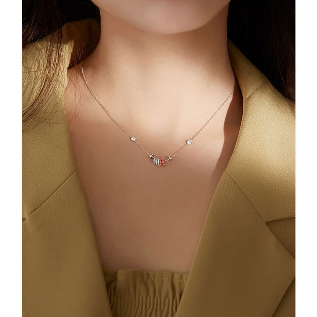 Rose gold necklace with a fine chain, featuring a cluster of colorful rings and small clear crystals.