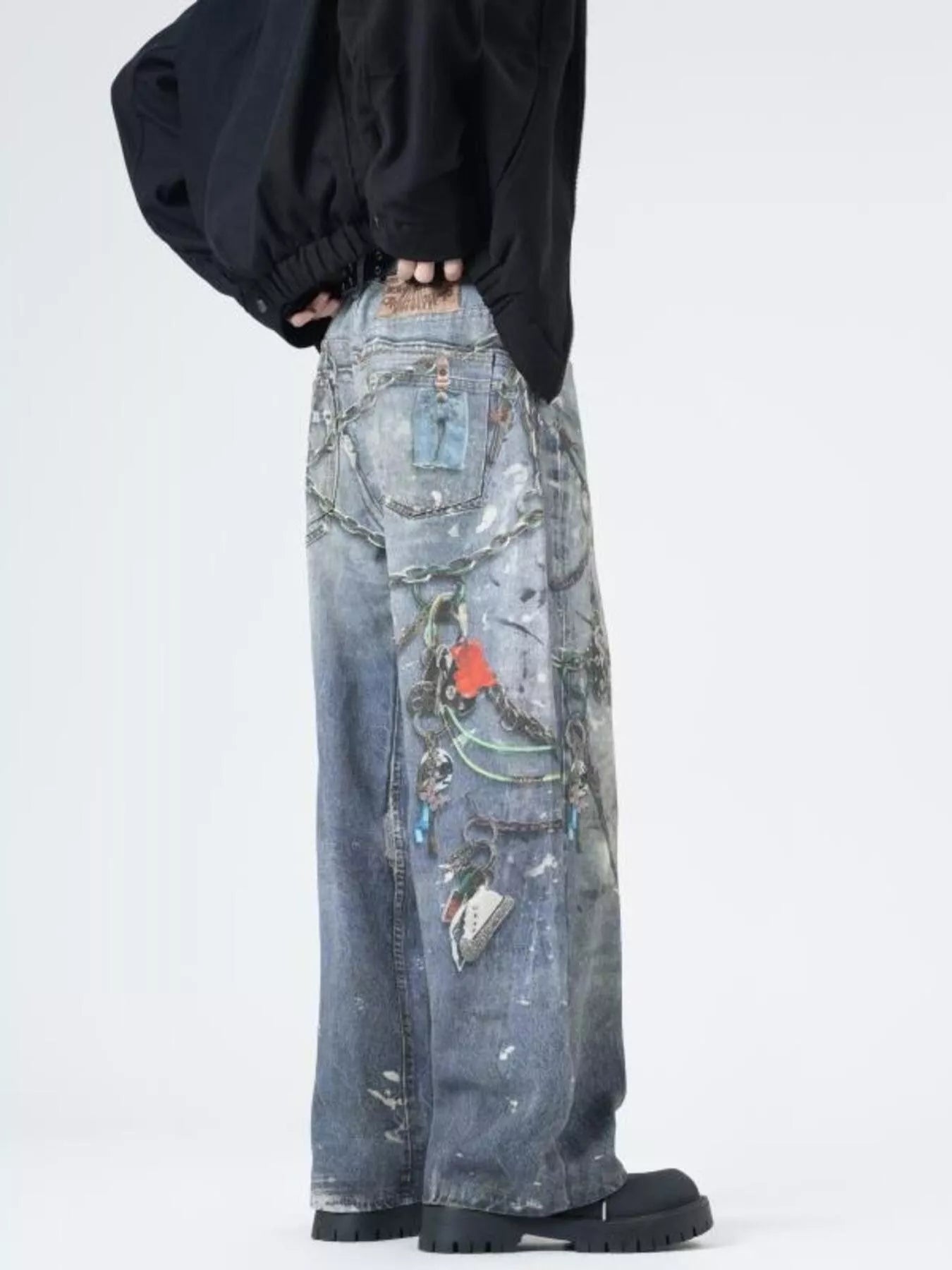 Men's wide-leg jeans in dusty blue denim with chain and keychain print details.