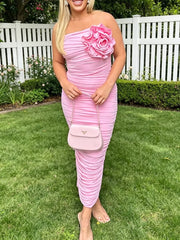 Pink ruched bodycon midi dress with floral appliqué and one-shoulder neckline.