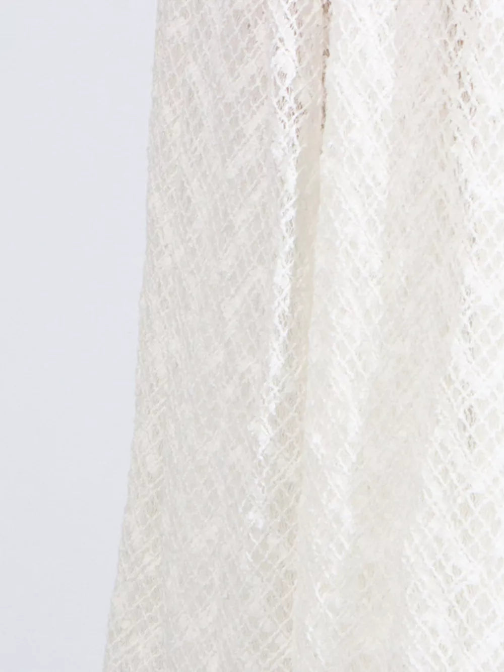 White lace maxi dress detail showing intricate diamond pattern fabric.