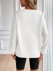 White relaxed fit sweatshirt with crewneck and long sleeves, styled with black biker shorts.