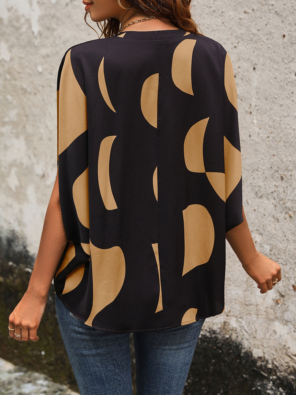 Black abstract print batwing blouse with wide sleeves and a relaxed fit.