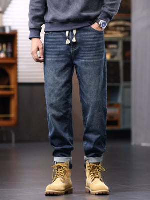 Men's relaxed fit dark wash denim jeans with drawstring and subtle horizontal stripe pattern.