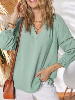 Light Green smocked long sleeve blouse with V-neck and eyelet detail on sleeves.