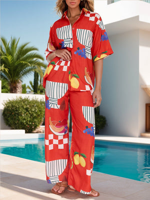 Orange-red camp shirt and wide-leg pants set with a tropical fruit print and checkered details.