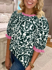 Damask print maternity blouse with ruffled neckline and half sleeves in green and white with pink trim.