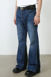 Medium wash denim bootcut trousers with black contrast panels and side slits.